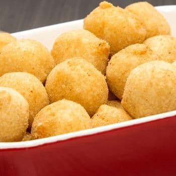 Bowl of golden Brazilian chicken croquettes (coxinhas) filled with shredded chicken and cream cheese.