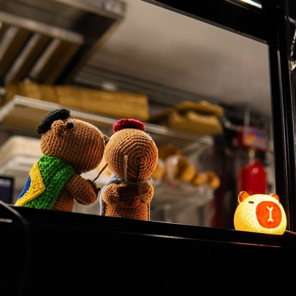 Crochet capybara mascots sitting at the food truck service window.