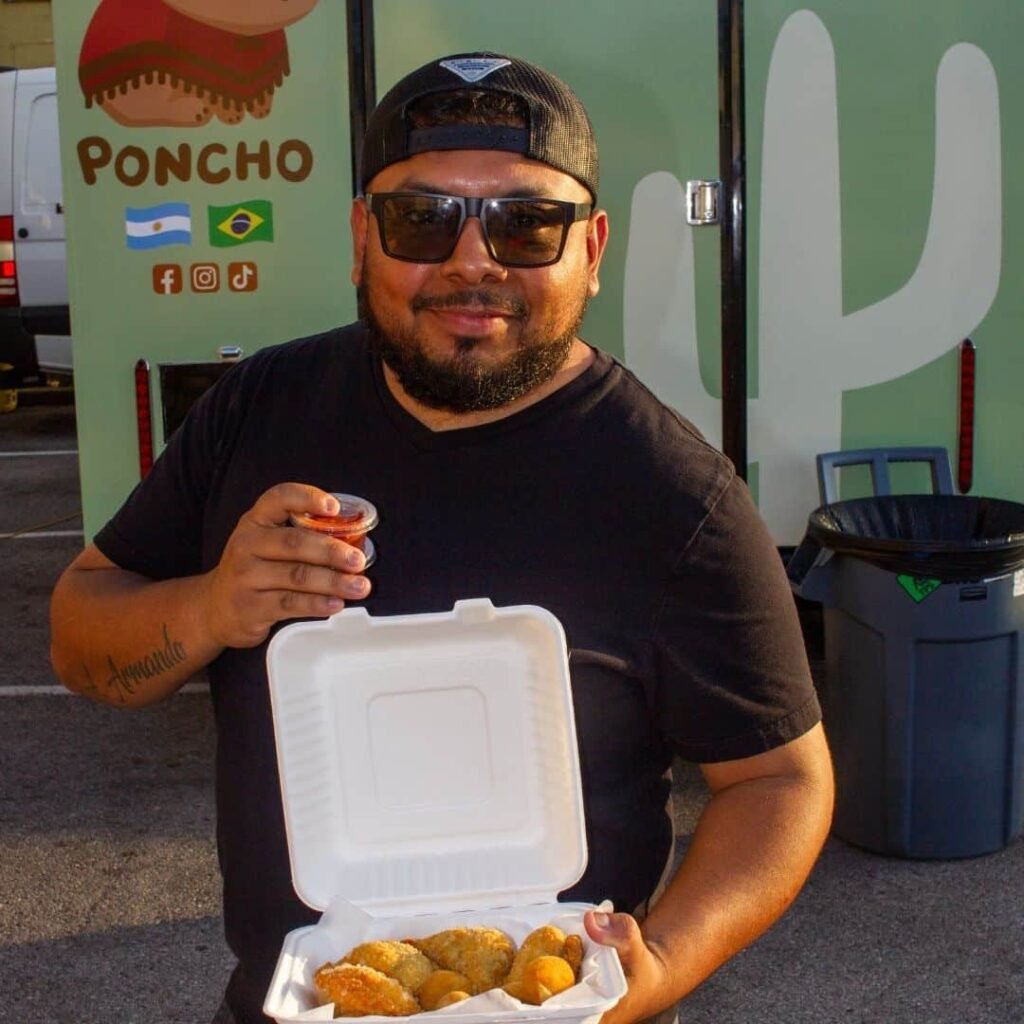 Man opening a takeout box filled with fresh South American snacks.