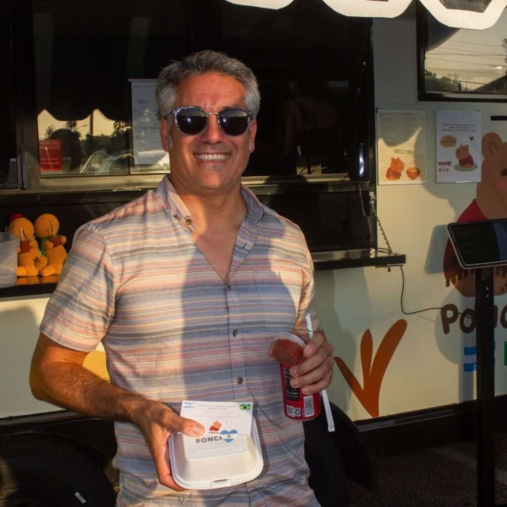 Smiling customer standing in front of the Poncho food truck with his order.