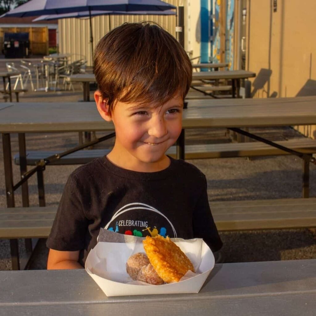 Young boy sitting at an outdoor table enjoying his meal from Poncho.